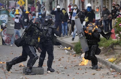 Varios policías corren a socorrer a un colega que fue alcanzado por un molotov durante una protesta contra el gobierno de Iván Duque en junio de 2021.