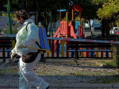 Una trabajadora municipal desinfecta las proximidades un parque infantil clausurado en la localidad madrileña de Alcobendas.
