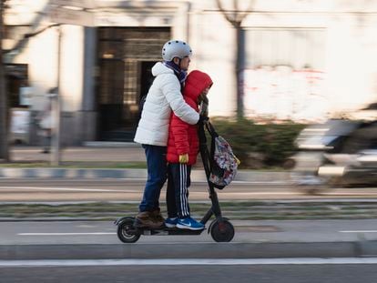 Un adulto se transporta junto a un menor en un patinete en la plaza Tetuán de Barcelona.