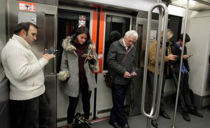 Viatgers del metro de Bilbao consulten el mòbil.
