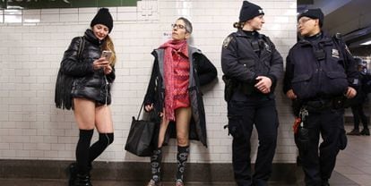 Dos participantes del 'No Pants Subway Ride' esperan el metro junto a dos policías.