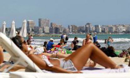 Centenares de turistas disfrutan del sol y las altas temperaturas en la playa del Postiguet de Alicante.