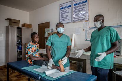El fisioterapeuta Víctor Kumi y el enfermero Patrice Koukou examinan el tobillo ulcerado de Kodzo en la sala de curas del hospital de Tsevié.