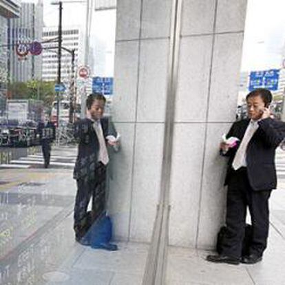 Un hombre de negocios delante de un tablero electrónico que muestra precios de las acciones del Nikkei