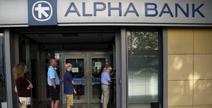 Varias personas esperan para hacer alguna gesti&oacute;n en una de las oficinas del bancogriego Alpha Bank.
