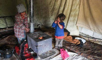 Dos niñas sirias tratan de entrar en calor en un campo de refugiados cercano a Damasco, este miércoles.
