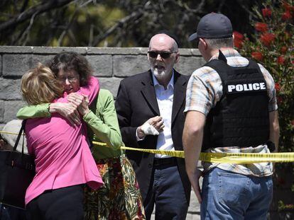 Dos mujeres se abrazan en el exterior de la sinagoga Chabad, en Poway, California.