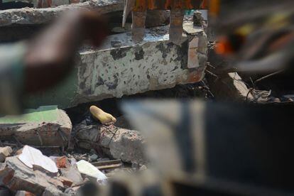Un cadáver entre los escombros del edificio textil derrumbado en Dacca (Bangladesh). Al menos 110 personas, la mayoría obreros, han muerto al derrumbarse un edificio que albergaba varias fábricas de tejidos.