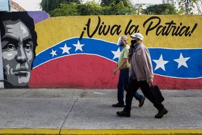 Dos ciudadanos caminan frente a un mural cerca de un colegio electoral, el domingo en Caracas.