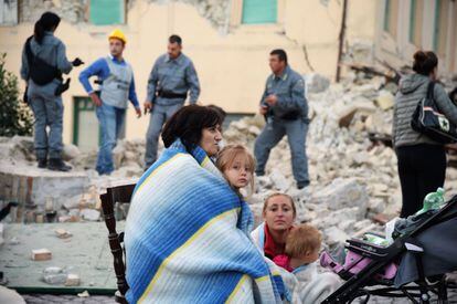 Varias familias abrigados con mantas descansan en medio de una calle de Amatrice.