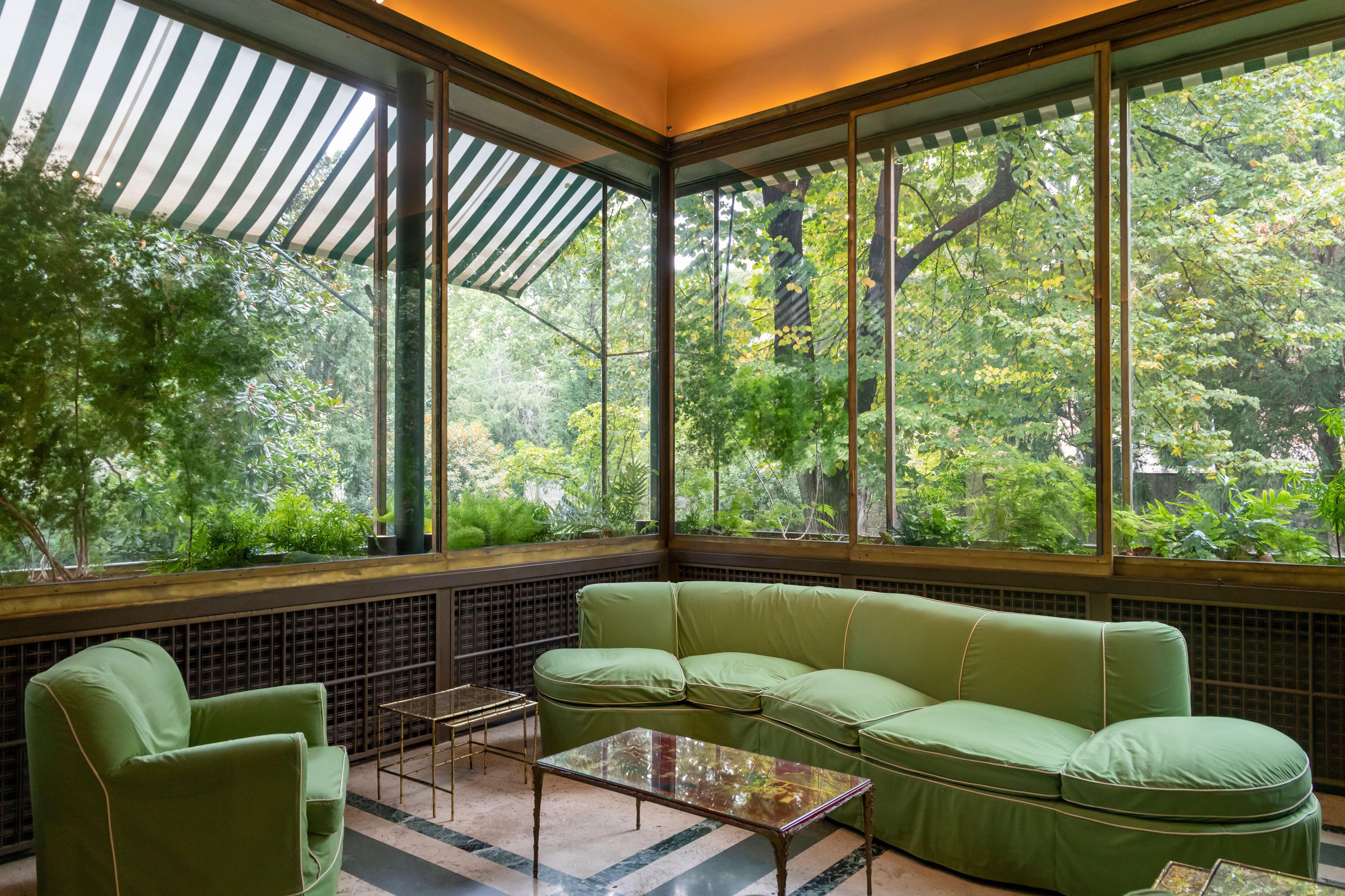 El invernadero, con sus muros de vidrio transparente que dan al jardín y su pavimento de travertino y mármol verde.