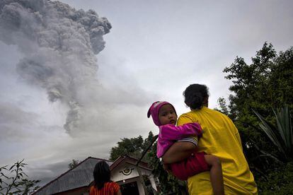 Una mujer con su hija en brazos contempla la erupción volcánica del Monte Sinabung en Sumatra, 14 de noviembre de 2013.