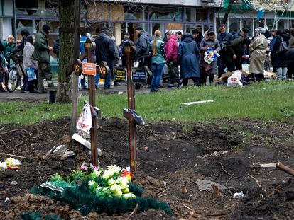 Residentes en Mariupol hacen cola buscando alimentos cerca de varias tumbas en una zona controlada por los rusos de la ciudad ucrania.