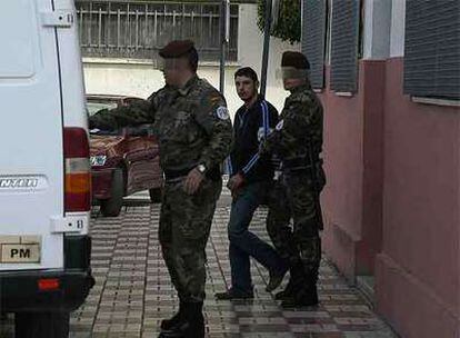 Dos policías militares trasladan a uno de los detenidos en Ceuta.