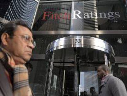 Dos viandantes pasan frente a la entrada de la sede de la agencia de calificación Fitch en Nueva York (EEUU). EFE/Archivo