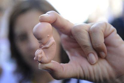 Manifestantes contra la ley del aborto exhiben la figura de un feto. La resistencia a la norma cobra fuerza entre los sanitarios.