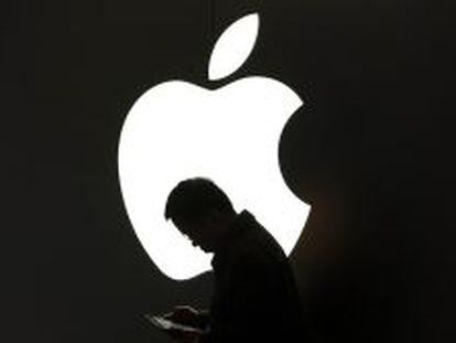 Un hombre lee junto a un logotipo de Apple