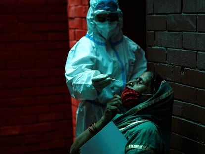 Un sanitario realiza una prueba PCR para detectar la covid-19 en una ciudadana en Nueva Delhi (India). 