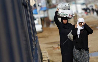 Refugiados sirios trasladan bolsas de alimentos este martes en el paso fronterizo de &Ouml;nc&uuml;pinar, Turqu&iacute;a.