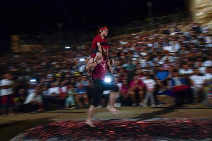 Un hombre lleva a un niño a su espalda mientras camina sobre las brasas durante la noche de San Juan en San Pedro Manrique (Soria).