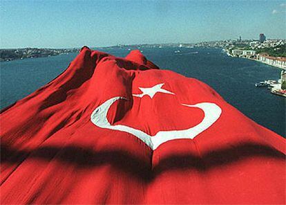 Vista de Estambul desde un puente sobre el Bósforo en el que aparece desplegada una gran bandera turca.