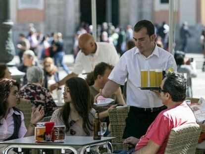 Un camarero sirve bebidas, en una terraza en la plaza de la Virgen de Valencia. 