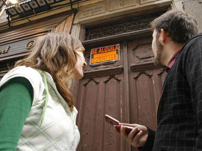 Una pareja de jóvenes mira un cartel de alquiler en Madrid, en una imagen de archivo.