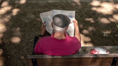 Una persona mayor leyendo el periódico en el parque Caramuel, en el barrio de Puerta del Ángel, Madrid.