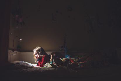 Una niña lee por la noche en su cama.
