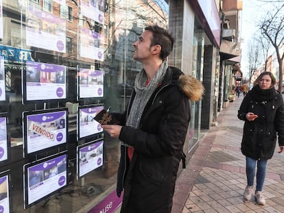 Un joven toma nota de pisos en venta en una inmobiliaria.