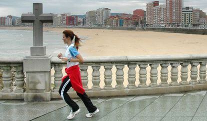 Una mujer hace ejercicio en el paseo marítimo de Gijón.