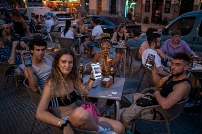 Un grupo de jóvenes muestran sus móviles en una terraza de la plaza de Cascorro, en Madrid. Ninguno de ellos compra periódicos ni sigue habitualmente los medios de comunicación.