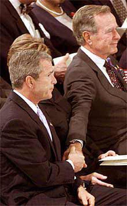 El antiguo presidente George Bush toma la mano de su hijo y actual presidente.