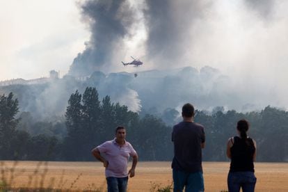 Un grupo de personas observa un helicóptero antiincendios en Belascoain (Navarra), el 19 de junio.