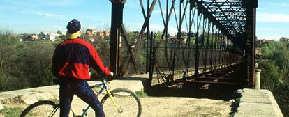 Un ciclista ante el puente de hierro sobre el río Guadarrama, cuya limpieza se incluye en un proyecto denunciado por Los Verdes.