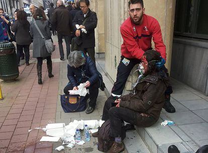 Un agent de seguretat privada ajuda una dona ferida després de l'atemptat a l'estació de metro de Maalbeek, al centre de Brussel·les (Bèlgica), el 22 de març del 2016. 
