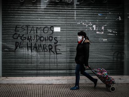 Una mujer camina frente a un grafiti en ciudad de Buenos Aires, en junio de este año.