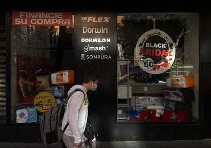 Un hombre pasa por el escaparate de un comercio que anuncia descuentos por el Black Friday, a 12 de noviembre de 2021, en Madrid.