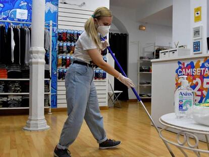 La dueña de una tienda de camisetas en Almería hace una limpieza en uno de los comercios de menos de 400 metros que han retomado su actividad con limitaciones de aforo y la puesta en marcha de medidas de higiene en la fase 1 de la desescalad.