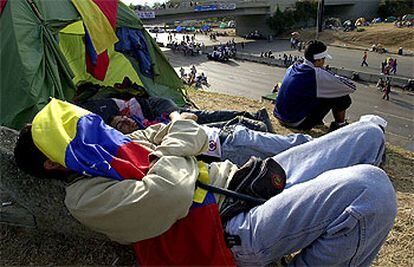 Varios manifestantes de la oposición duermen junto a una autopista de Caracas.