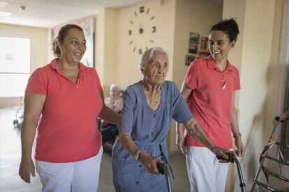 Martina Hernández, de 95 años, asistida por dos auxiliares en la residencia Servitrés de Santa Cruz de Retamar, Toledo.