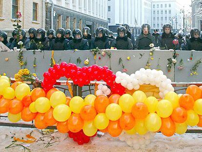 Policías antidisturbios, con escudos decorados con flores y detrás de una guirnalda de globos con los colores de la oposición, montan guardia delante de la sede de la Presidencia, ayer en Kiev.