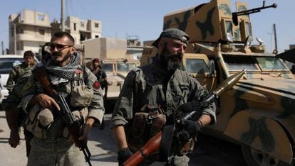 Combatientes de las Fuerzas Democr&aacute;ticas Sirias, junto a un veh&iacute;culo militar en Raqa, en el norte de Siria, el pasado mes de octubre.