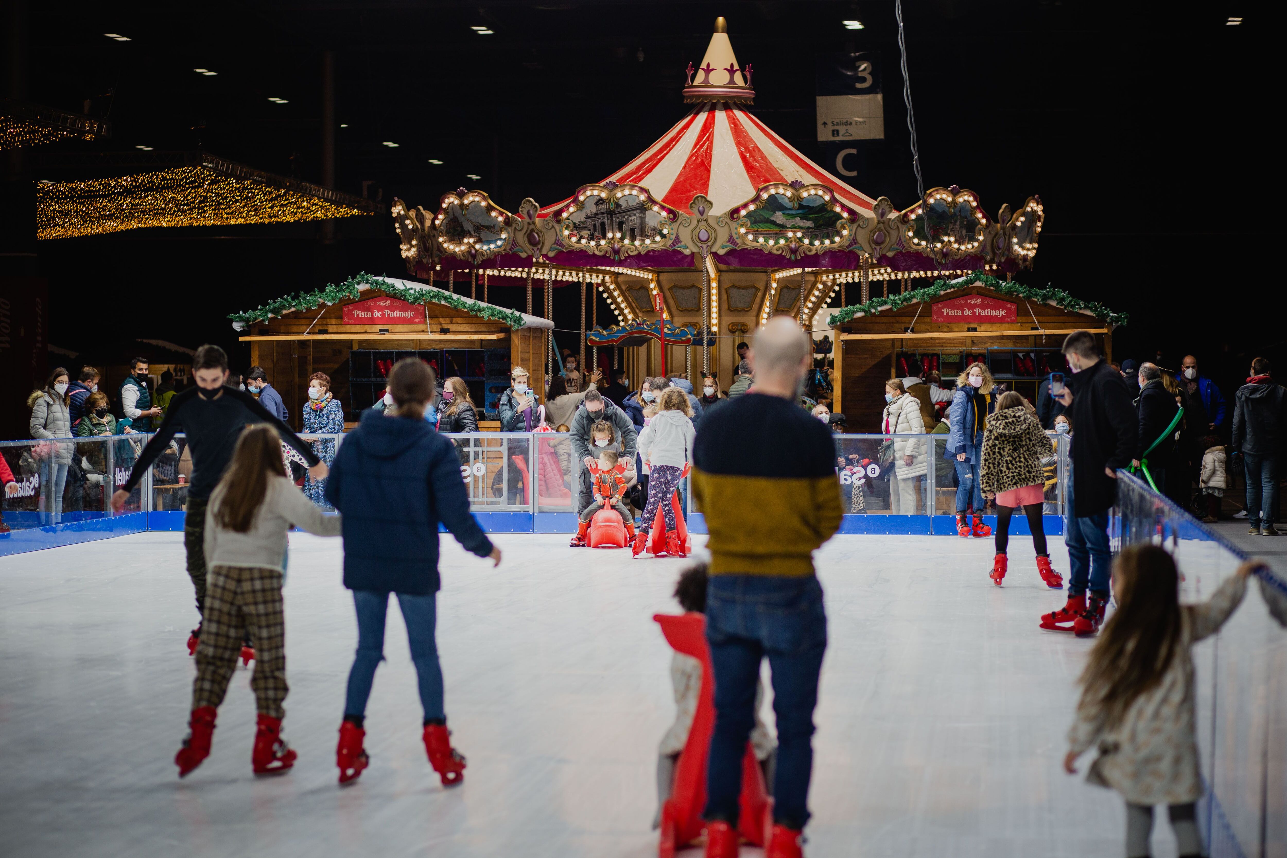 Unos niños se divierten en la pista de hielo sintético del Pueblo de la Navidad, en Joy to the world.