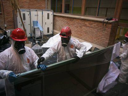 Trabajadores retiran una de las pizarras con amianto en un colegio de Cataluña. 