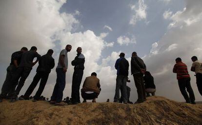 Unos palestinos observan las labores de rescate de Hamás mientras buscan los restos de unos excavadores fallecidos en una operación israelí contra un túnel.