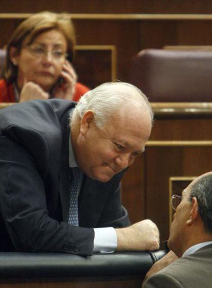 Moratinos (izquierda) conversa con un diputado en el pleno.