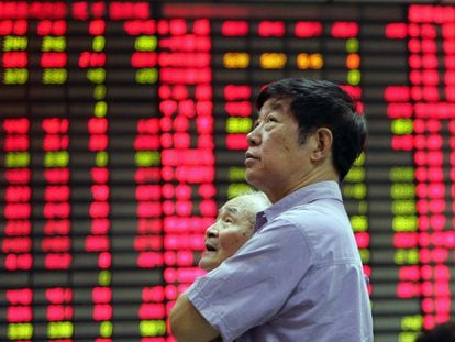 Dos inversores miran los paneles de la Bolsa de Shanghai.