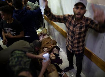 Un hombre pide ayuda para atender a dos heridos que permanecen en el suelo del hospital Nasser en Jan Yunis, tras un ataque israelí este domingo. 