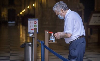 Un hombre usa un dispensador de gel hidroalcohólico en la catedral de Sevilla.